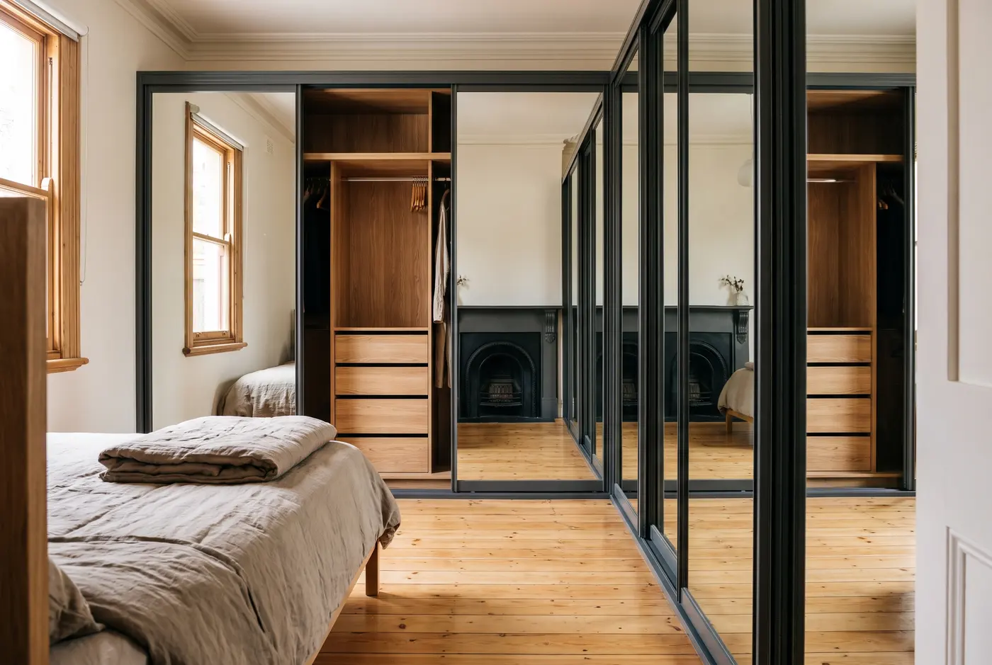 Full-height mirrored sliding wardrobe doors visually widening a narrow bedroom in a Norwood terrace cottage